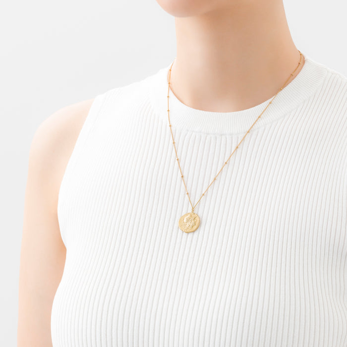 Best Japanese Jewelry Brands: 21 Labels to Know (2026) 15 MARIHA Ancient Memories gold-tone coin necklace styled over a white top.